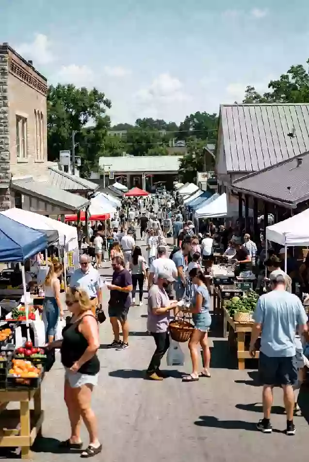 Shoppers at outdoor farmers market with produce and vendors