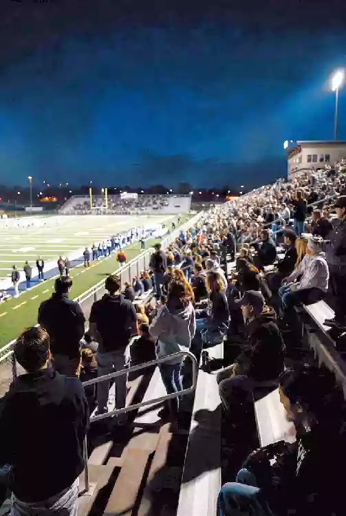 Vertical photo of fans watching a high school football game under the lights in Shawnee
