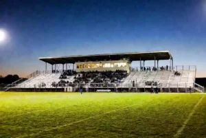 Wide view of a high school football stadium at dusk under stadium lights in Holdenville Oklahoma