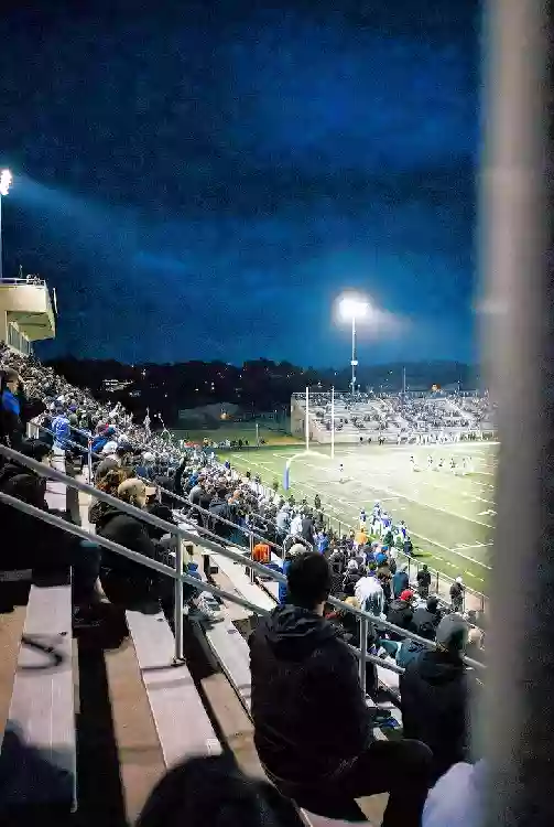 Vertical photo of fans watching a high school football game under the lights in Holdenville