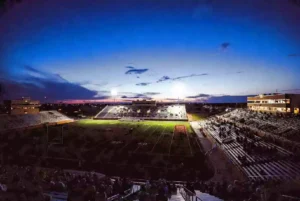 Wide view of a high school football stadium at dusk under stadium lights in Norman Oklahoma