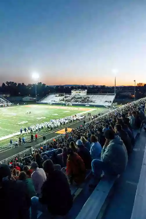 Vertical photo of fans watching a high school football game under the lights in Norman