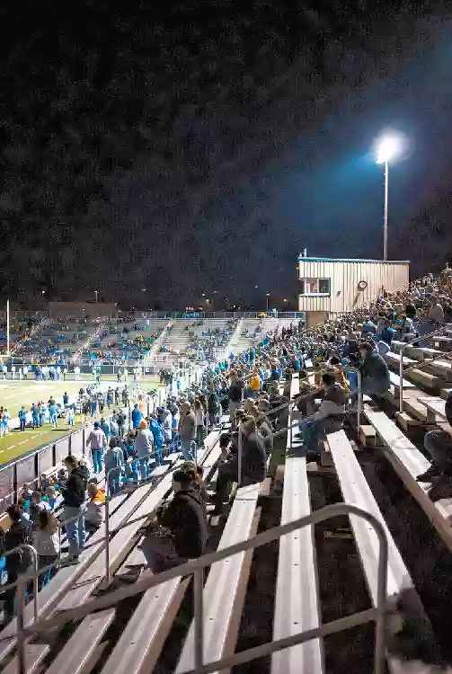 Vertical photo of fans watching a high school football game under the lights in central Oklahoma