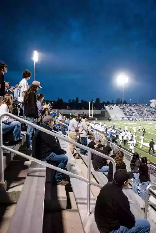 Vertical photo of fans watching a high school football game under the lights in McAlester