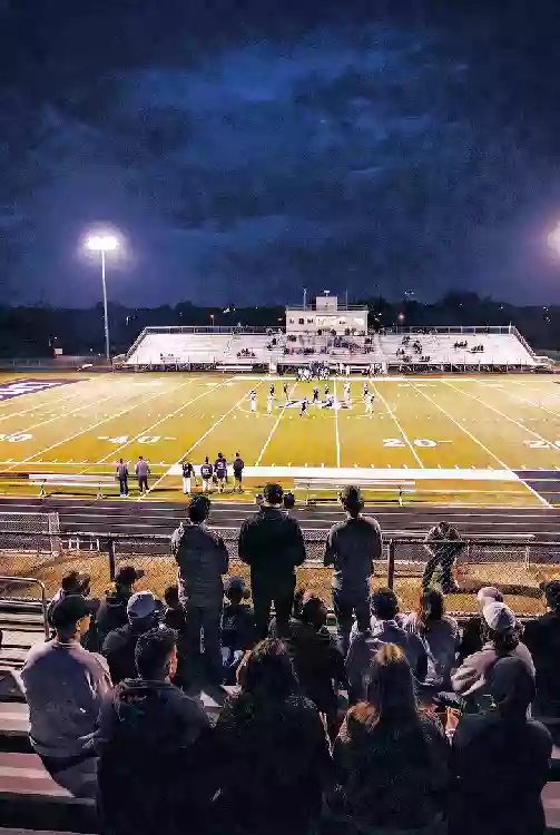 Vertical photo of fans watching a high school football game under the lights in Sapulpa