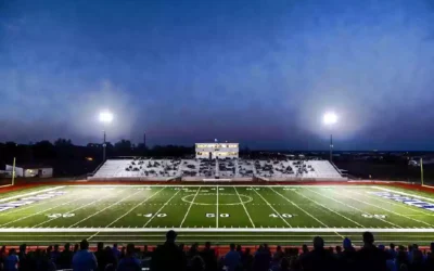 Wide view of a high school football stadium at dusk under stadium lights in Okmulgee Oklahoma