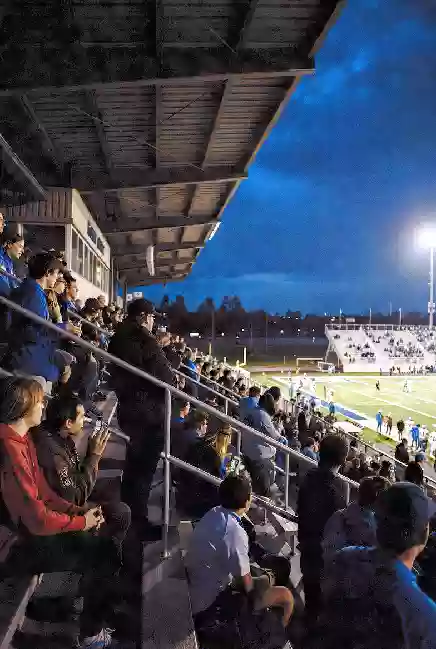 Vertical photo of fans watching a high school football game under the lights in Okmulgee