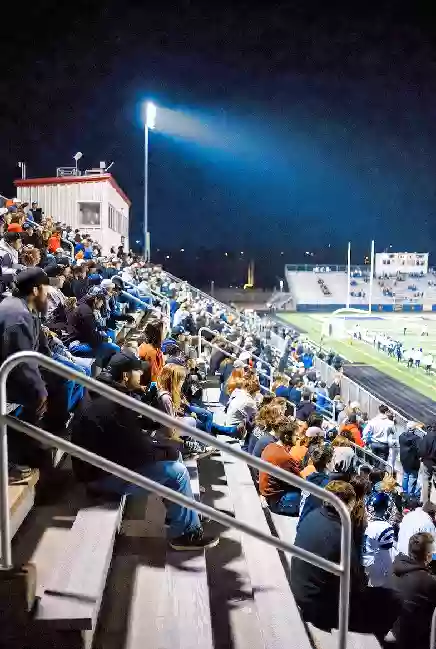 Vertical photo of fans watching a high school football game under the lights in Eufaula