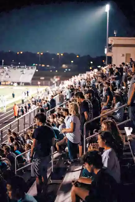 Vertical photo of fans watching a high school football game under the lights in Stillwater