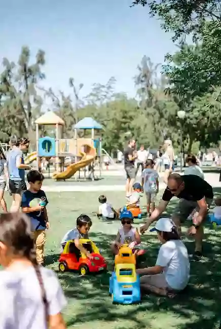 Children and families enjoying free outdoor play activities at a park in Ada