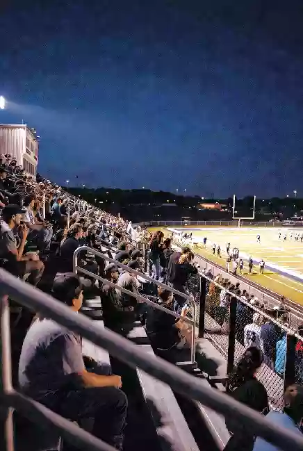 Vertical photo of fans watching a high school football game under the lights in Bixby