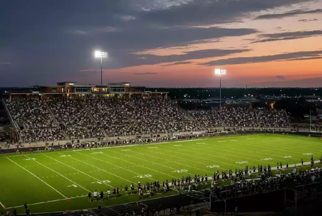 Wide view of a high school football stadium at dusk under stadium lights in Owasso Oklahoma