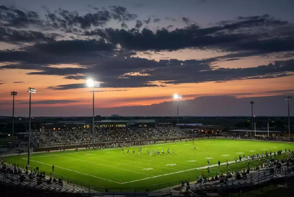 Wide view of a high school football stadium at dusk under stadium lights in Weatherford Oklahoma