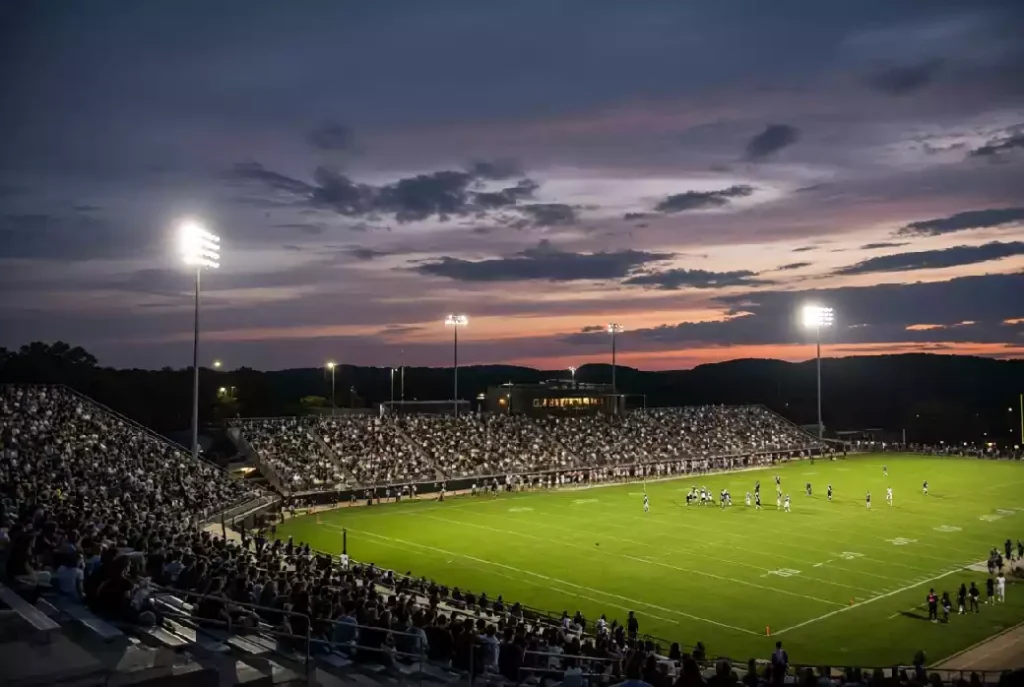 Wide view of a high school football stadium at dusk under stadium lights in Bartlesville Oklahoma