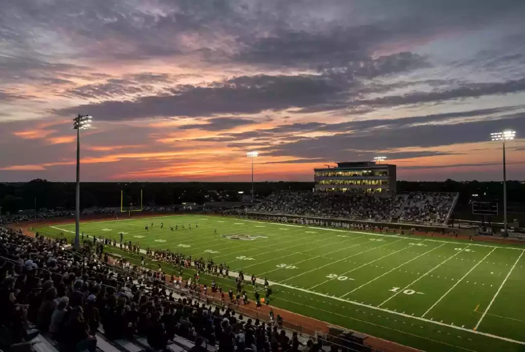 Wide view of a high school football stadium at dusk under stadium lights in Ponca City Oklahoma