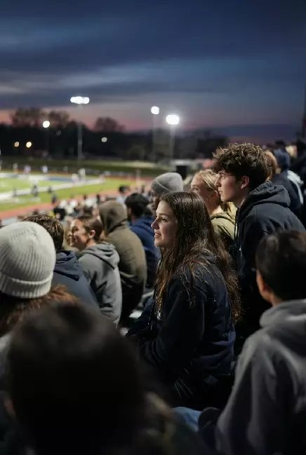 Vertical photo of fans watching a high school football game under the lights in Ponca City