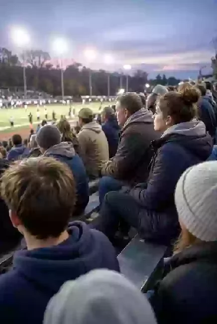 Vertical photo of fans watching a high school football game under the lights in Sand Springs