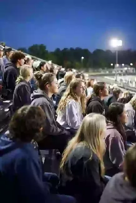 Vertical photo of fans watching a high school football game under the lights in Sequoyah County