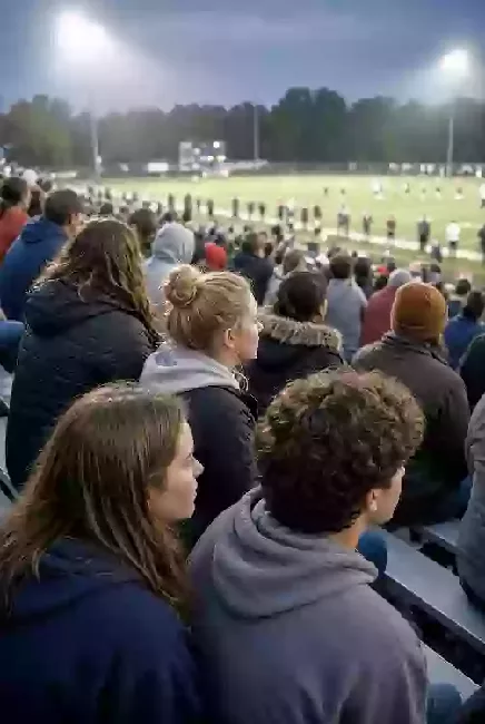 Vertical photo of fans watching a high school football game under the lights in Seminole County