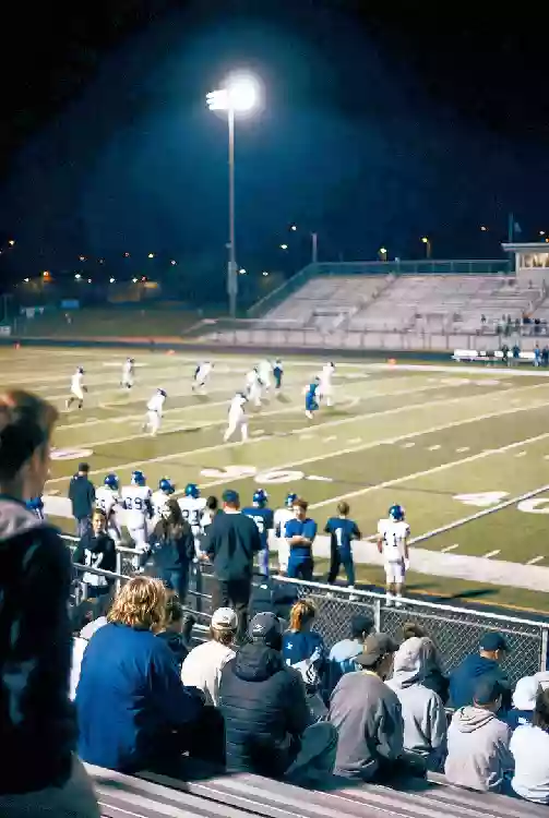 Vertical photo of fans and players during a high school football game under the lights in Muskogee