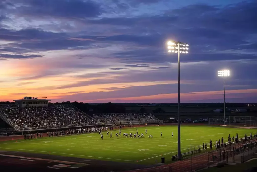 Wide view of a high school football stadium at dusk under stadium lights in Texas County Oklahoma