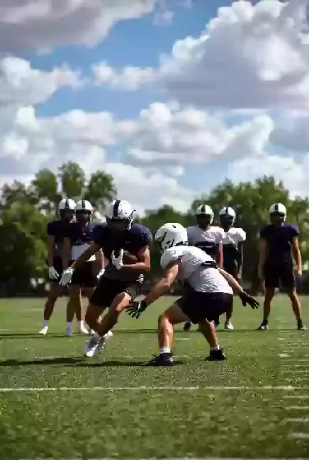 Vertical photo of high school football players practicing on the field in Texas County Oklahoma