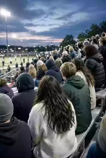 Vertical photo of fans watching a high school football game under the lights in Texas County