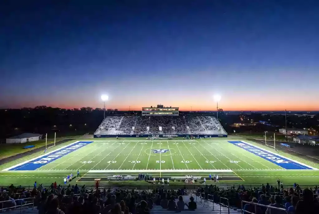 Wide view of a high school football stadium at dusk under stadium lights in Edmond Oklahoma