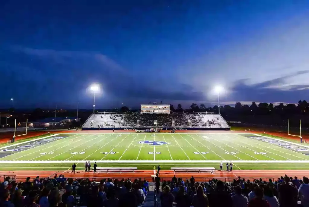 Wide view of a high school football stadium at dusk under stadium lights in Oklahoma City