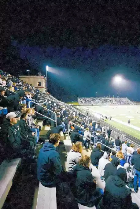 Vertical photo of fans watching a high school football game under the lights in Oklahoma City