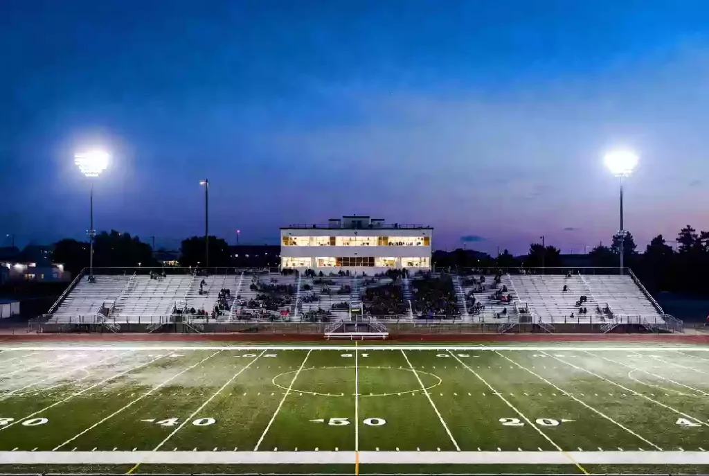 Wide view of a high school football stadium at dusk under stadium lights in Yukon Oklahoma