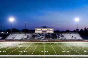 Wide view of a high school football stadium at dusk under stadium lights in Yukon Oklahoma
