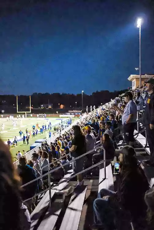 Vertical photo of fans watching a high school football game under the lights in Yukon
