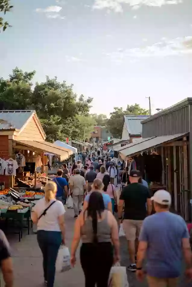 Busy outdoor community market with people among vendor stalls