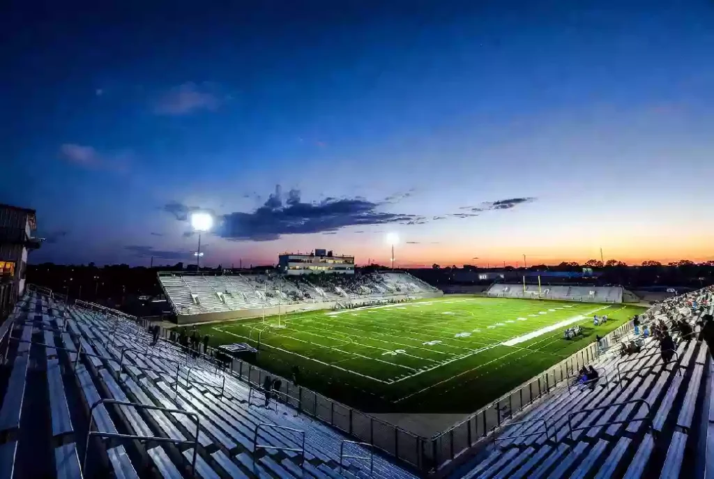 Wide view of a high school football stadium at dusk under stadium lights in Tulsa Oklahoma