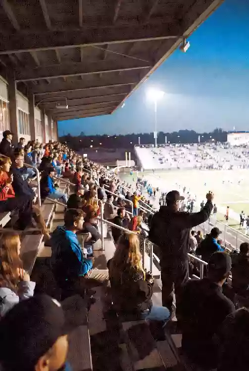 Vertical photo of fans watching a high school football game under the lights in Tulsa